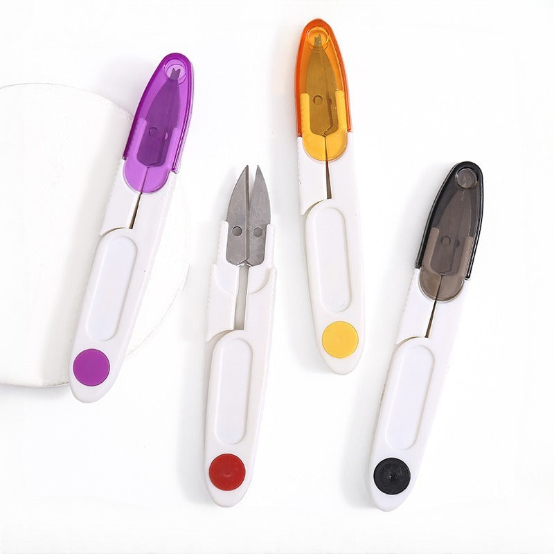 Four small spring-loaded thread snips with white handles and colored plastic ends on a white background
