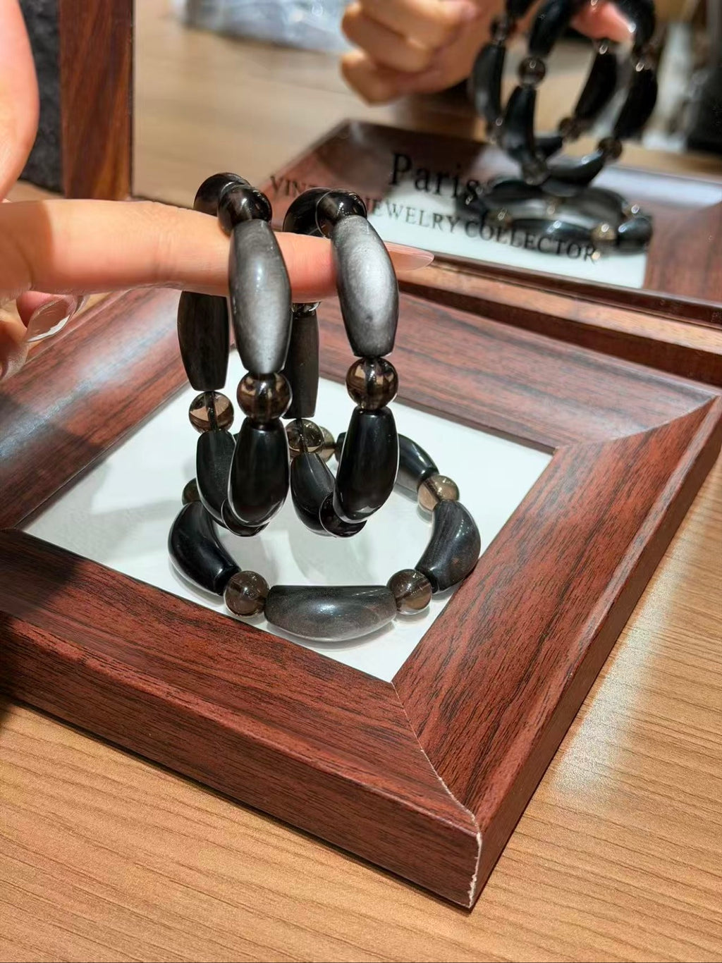 Hand holding silver obsidian petal-tube bracelet strands