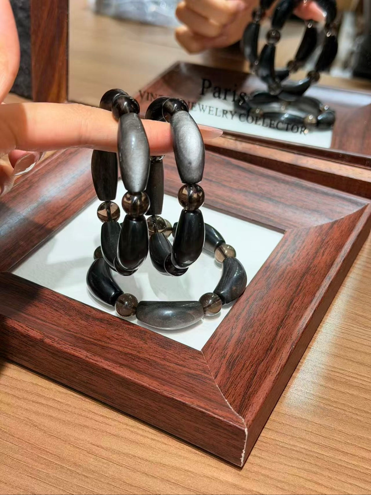 Hand holding silver obsidian petal-tube bracelet strands