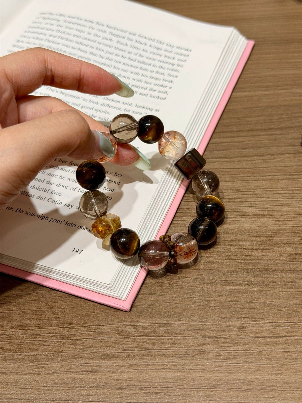 Brown, black and clear gemstone beaded bracelet held in a hand