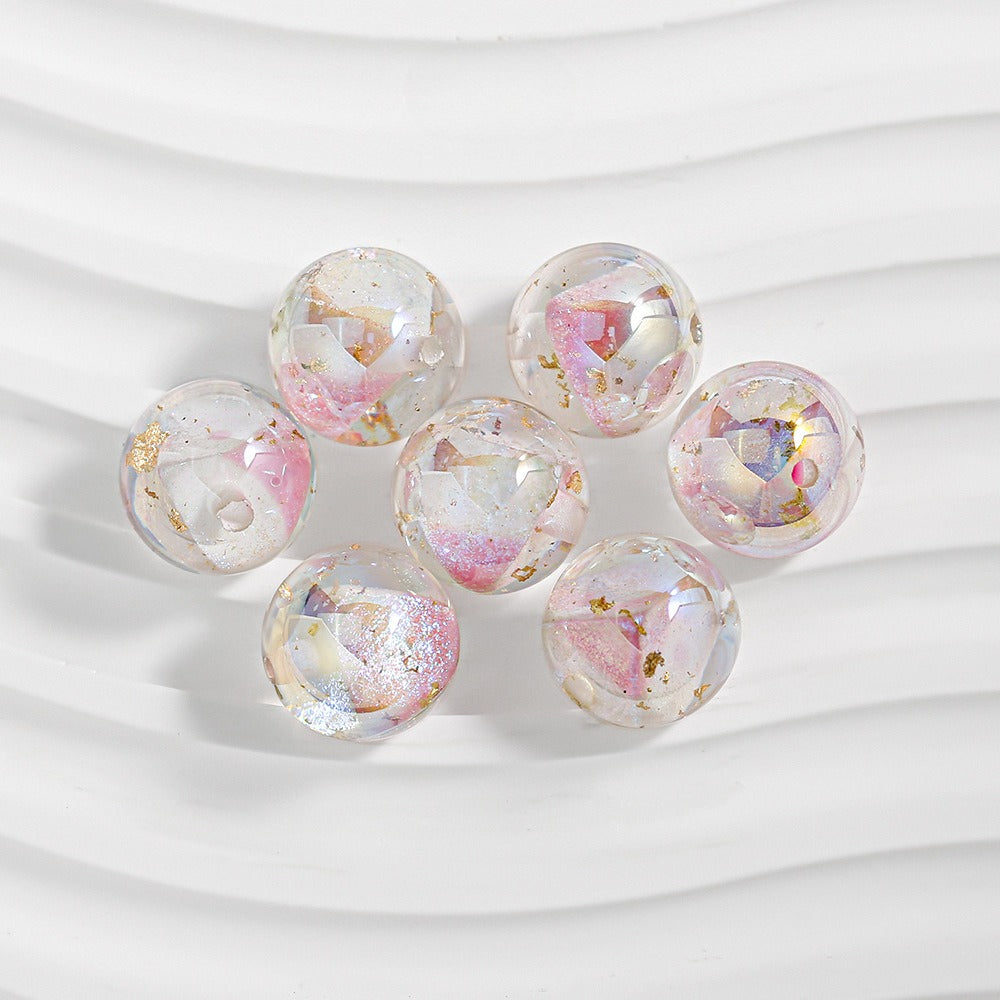 Seven clear resin beads with pink floral inclusions and gold foil