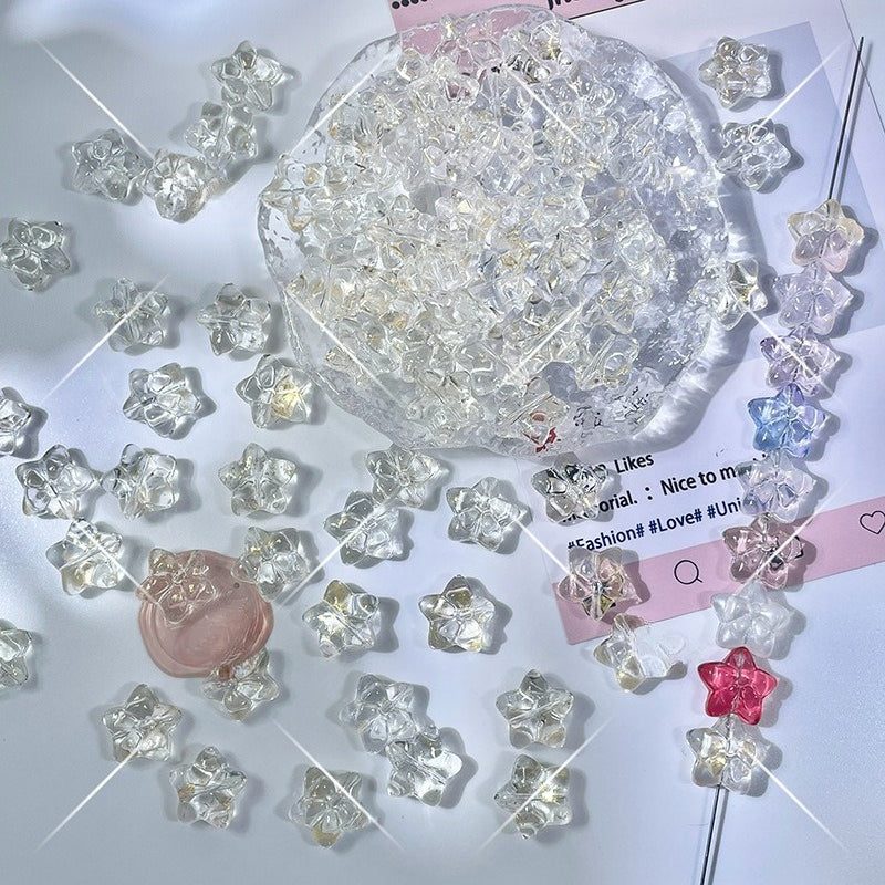 Clear faceted star-shaped glass beads in pink, purple, and blue on a white surface