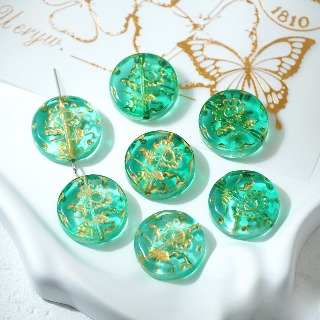 Seven teal 18mm gold-painted Czech-style glass sunflower beads on a white decorative surface