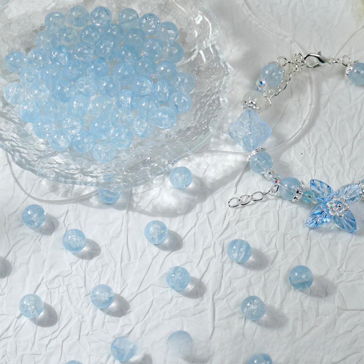 Light blue glass bead bracelet beside a bowl of loose blue beads