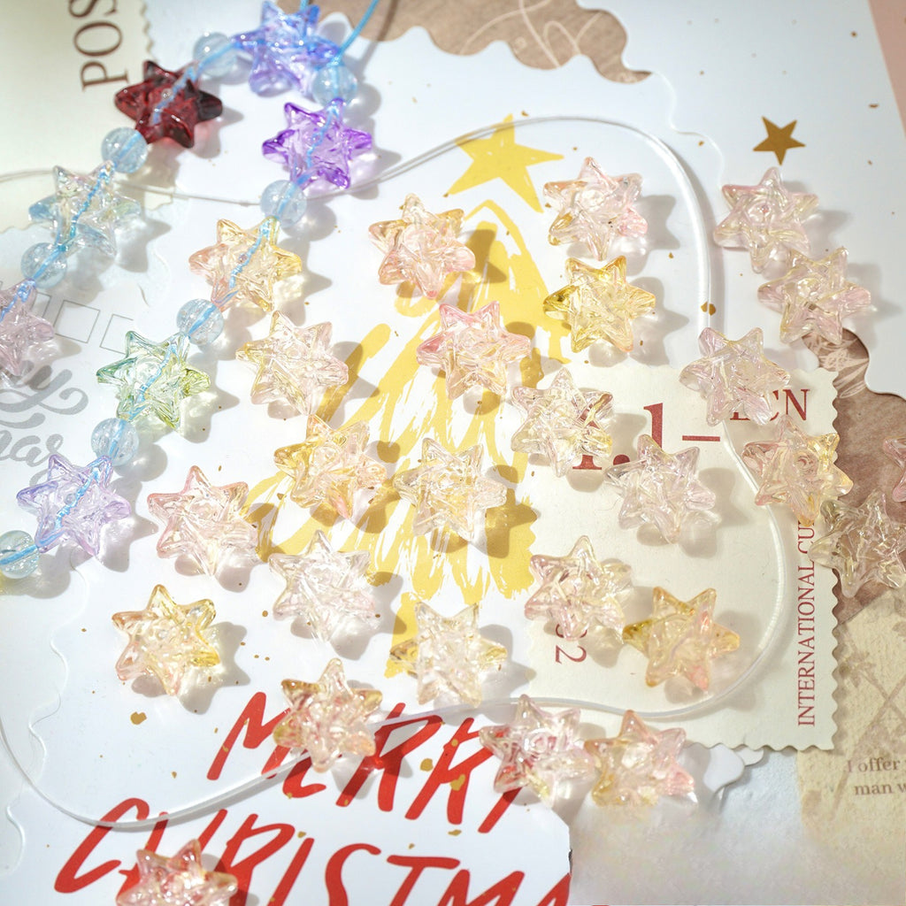 Translucent star-shaped glass beads in pastel pink, yellow, purple, and blue on a Christmas card