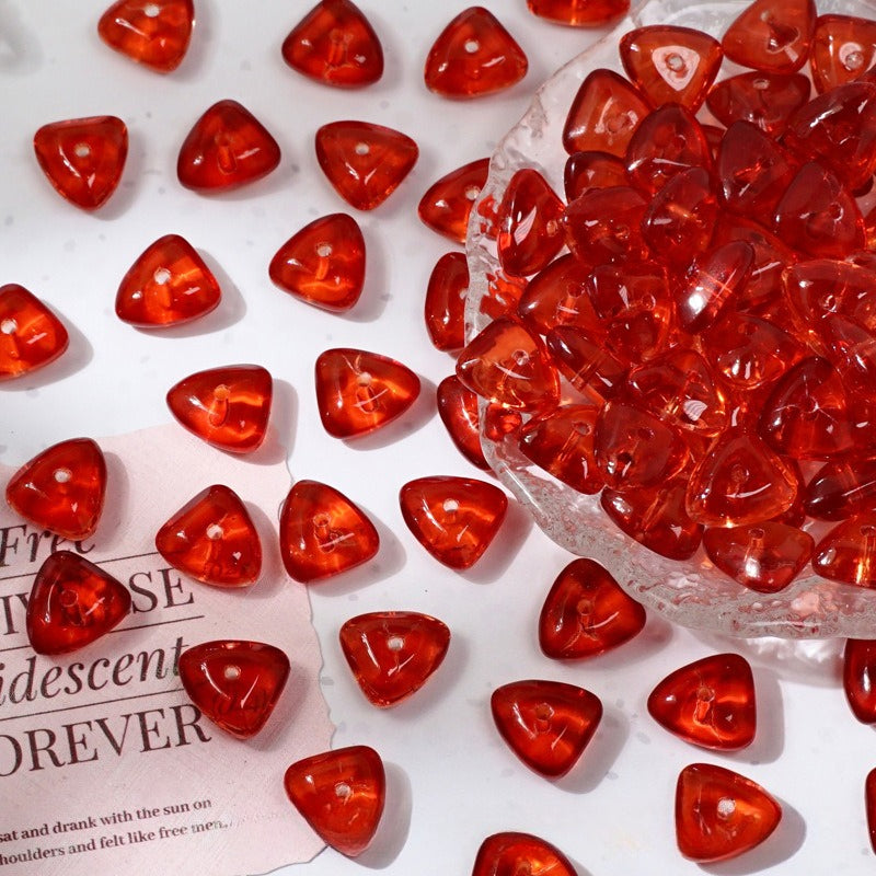 Red translucent heart-shaped glass beads scattered on white and piled in a clear bag