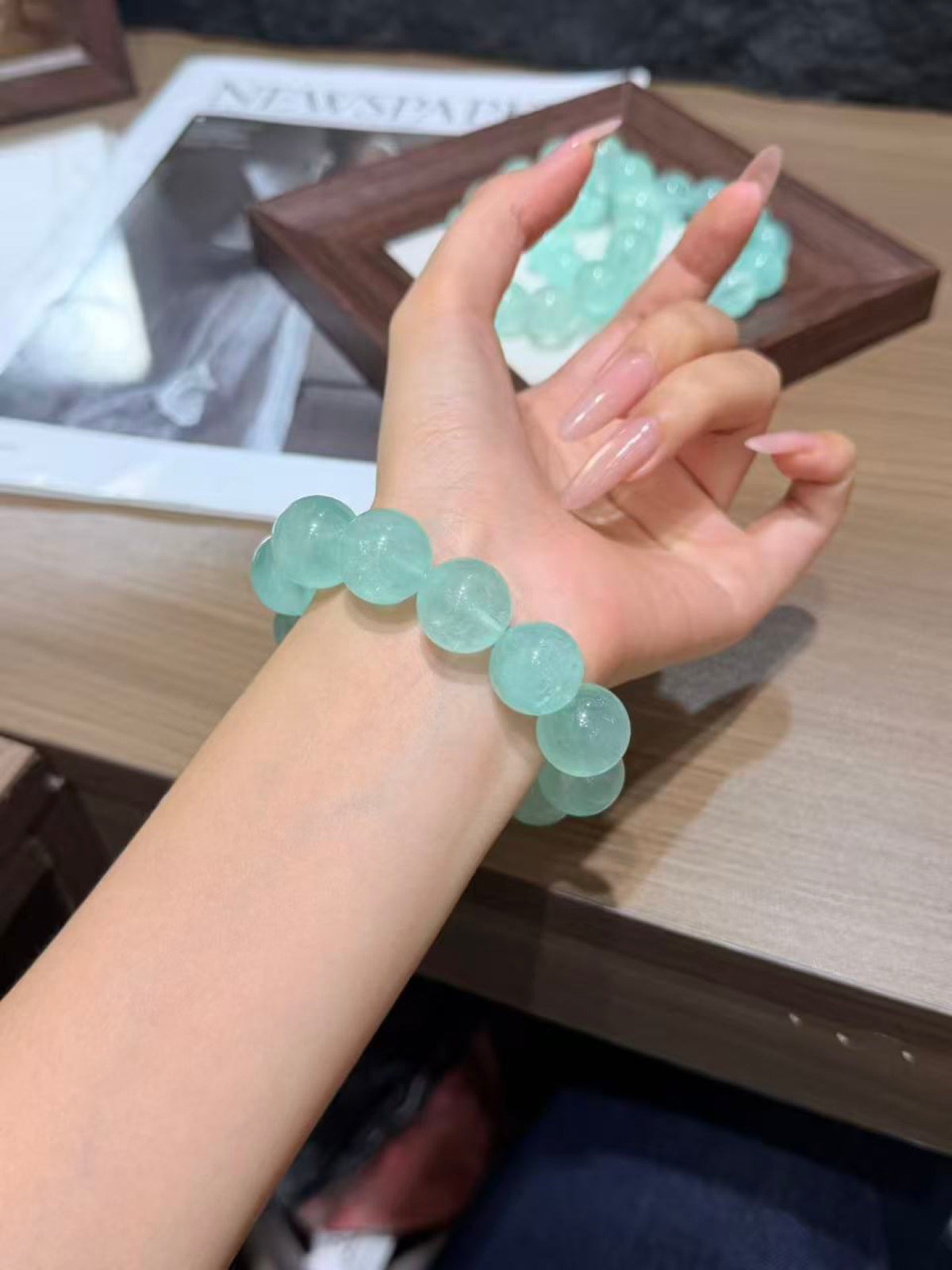 Wrist wearing a mint green fluorite bracelet of large translucent round beads