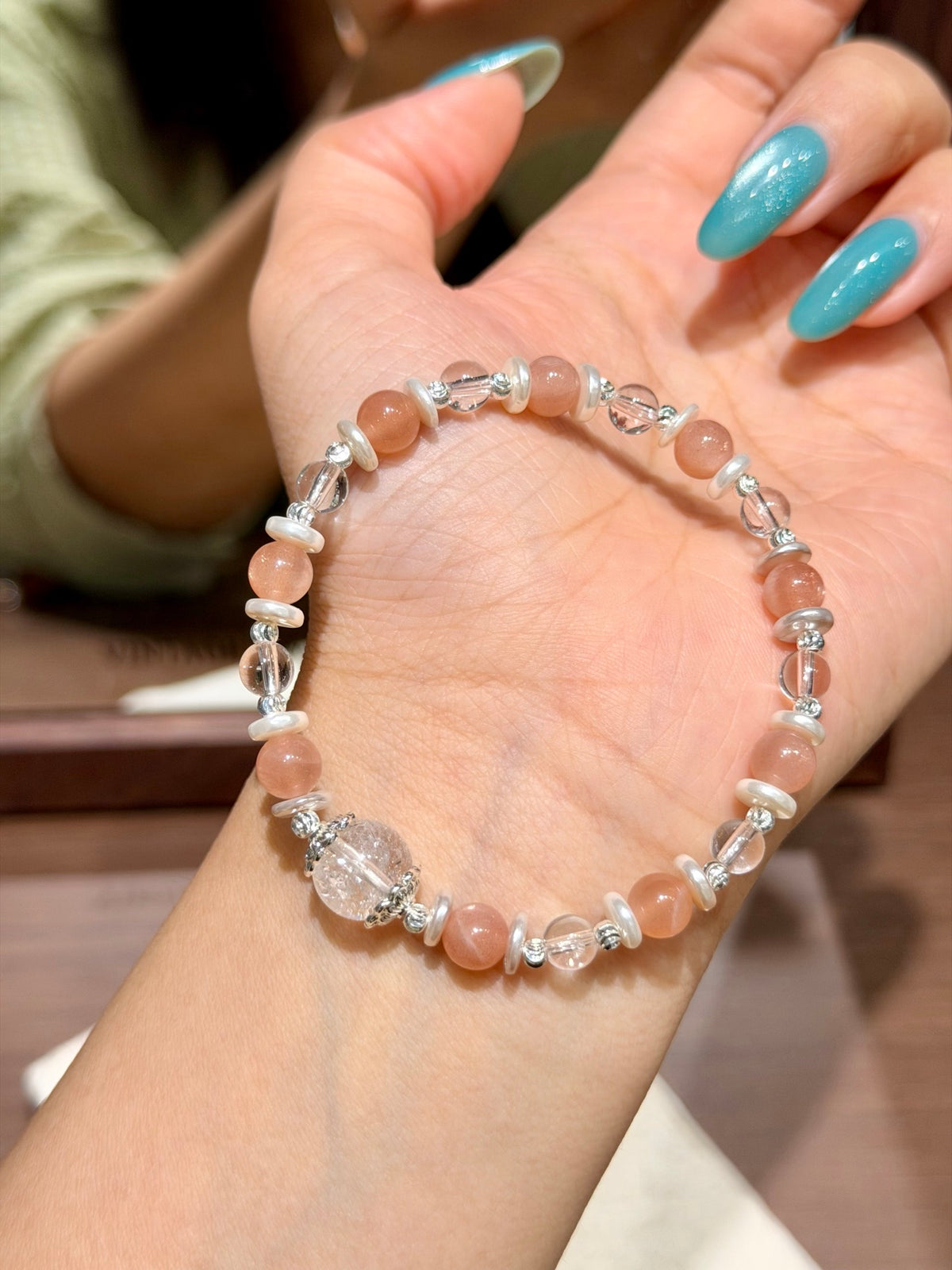 Hand holding warm glow orange moonstone bracelet