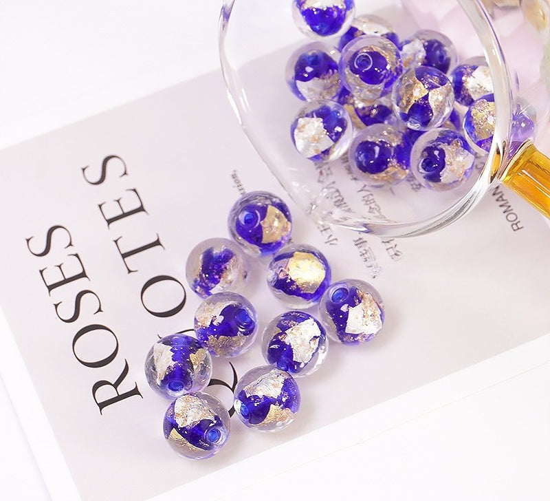 Deep blue-purple gold-flake glass beads spilling from a glass bowl onto a printed card