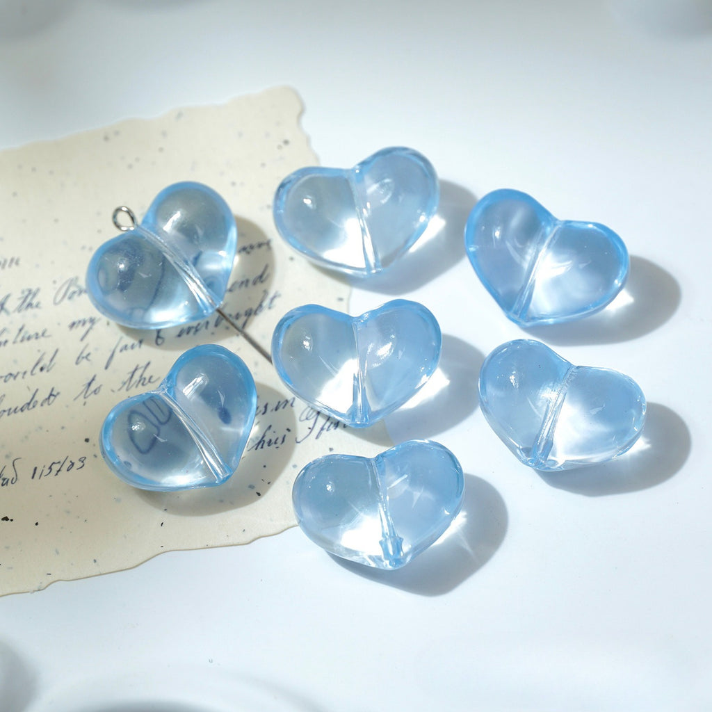 Seven light blue translucent heart-shaped glass beads with metal loop tops on white