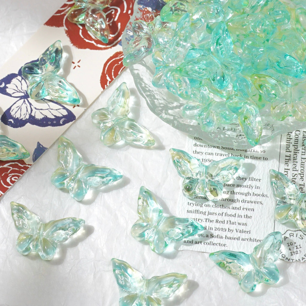 Clear butterfly beads in light aqua and iridescent green tones scattered on white