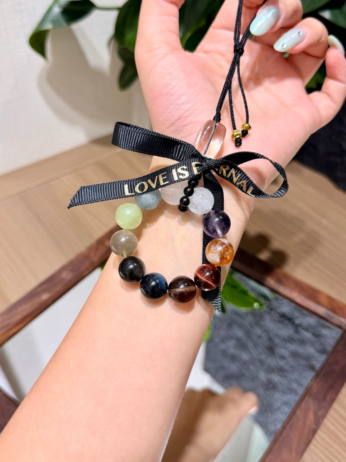 Multi-gemstone beaded car charm with black ribbon bow printed LOVE IS ARRIVAL in gold