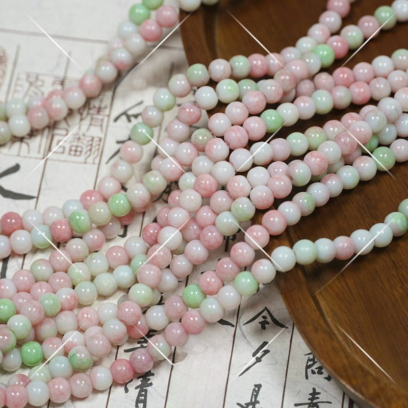 Multi-strand pastel porcelain beads in pink, mint green, white on wooden tray