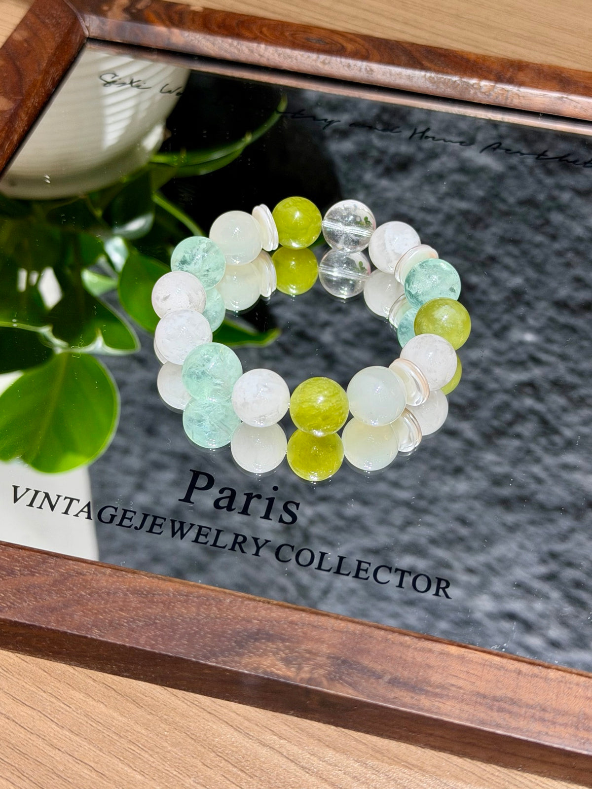 Hand holding spring stream bracelet with snowflake phantom quartz over tray
