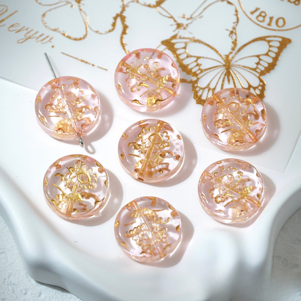 Seven pink 18mm gold-painted Czech-style glass sunflower beads on a white decorative surface