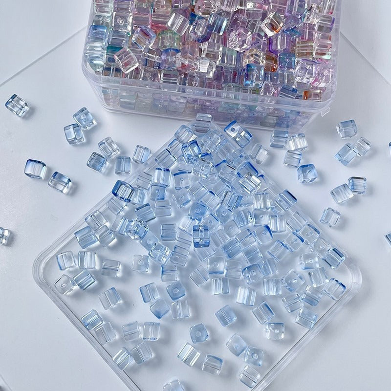 Clear square glass beads with blue edges scattered on white