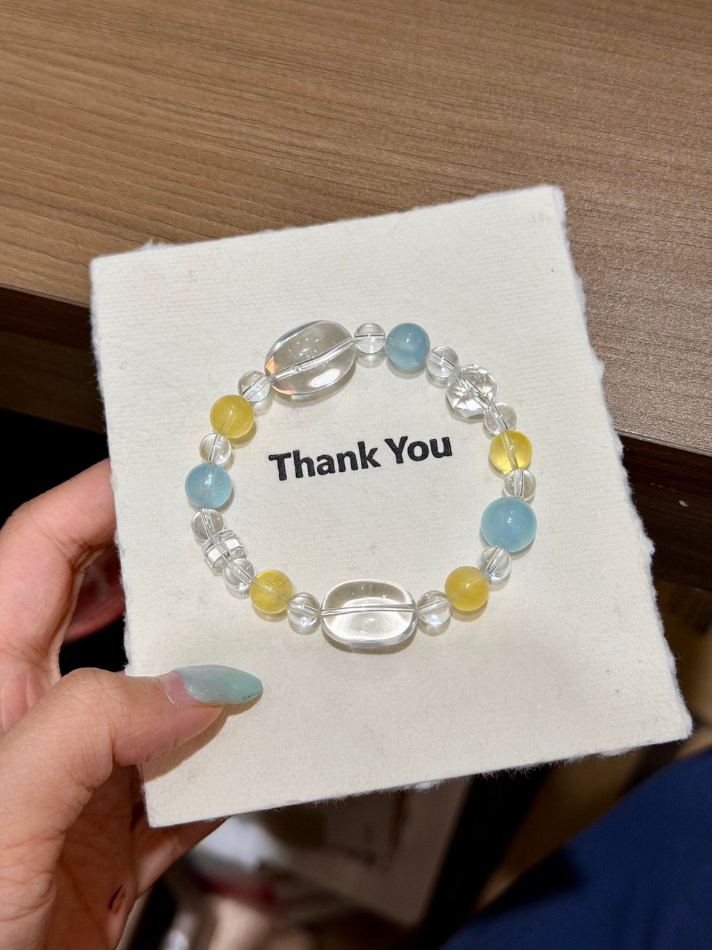 Hand holding sea frost bracelet with faceted white crystal over book