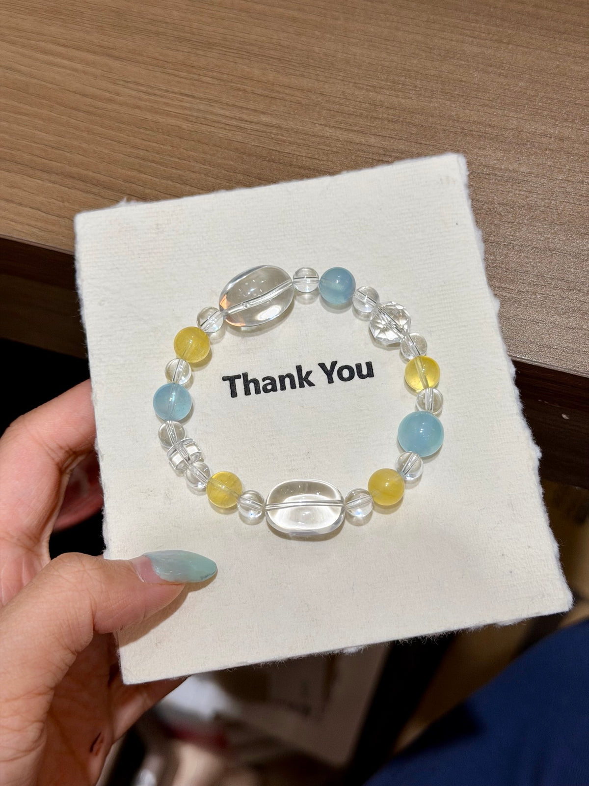 Hand holding sea frost bracelet with faceted white crystal over book