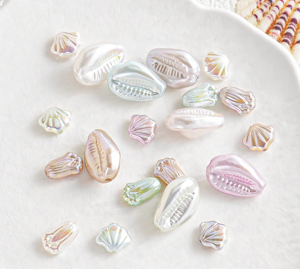 Iridescent shell-shaped faux pearl beads scattered on a white surface