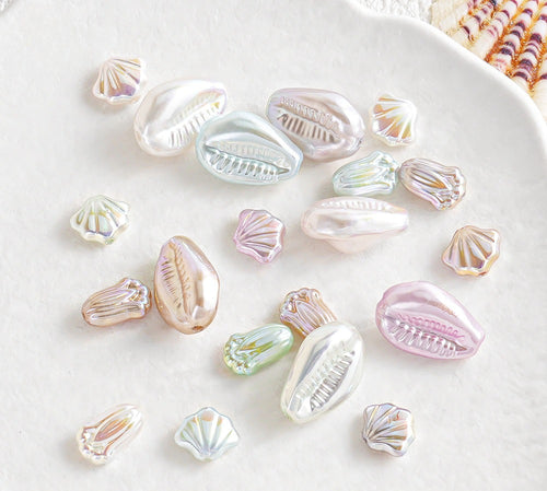 Iridescent shell-shaped faux pearl beads scattered on a white surface