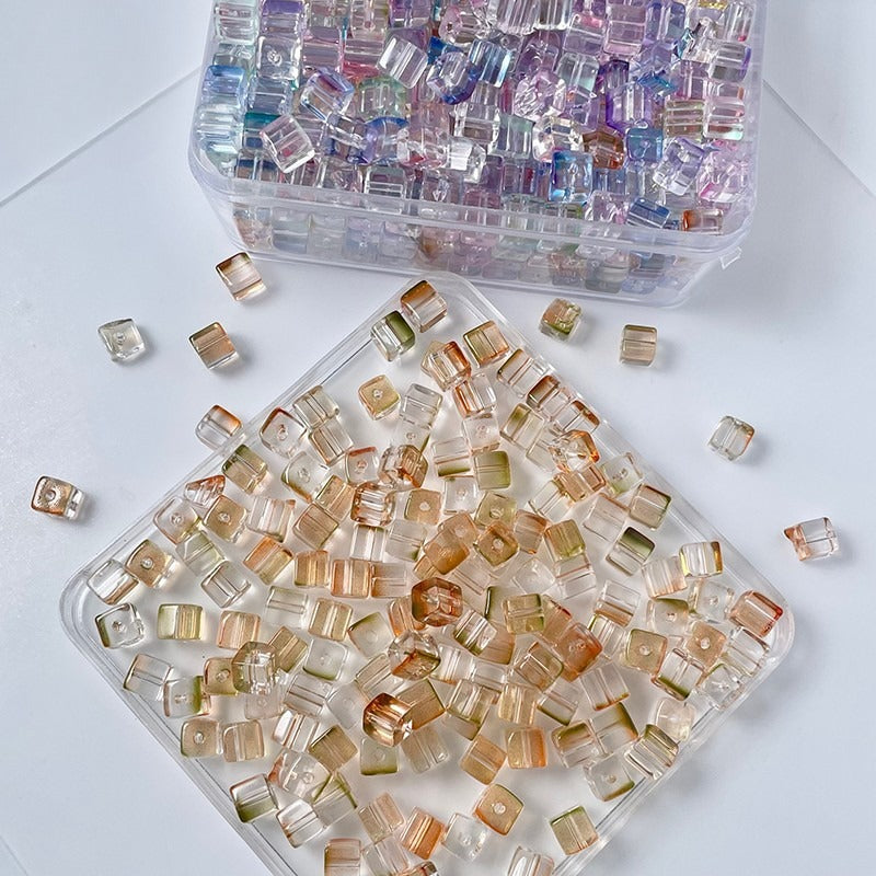 Two clear trays of small pastel rainbow rectangular faceted glass beads