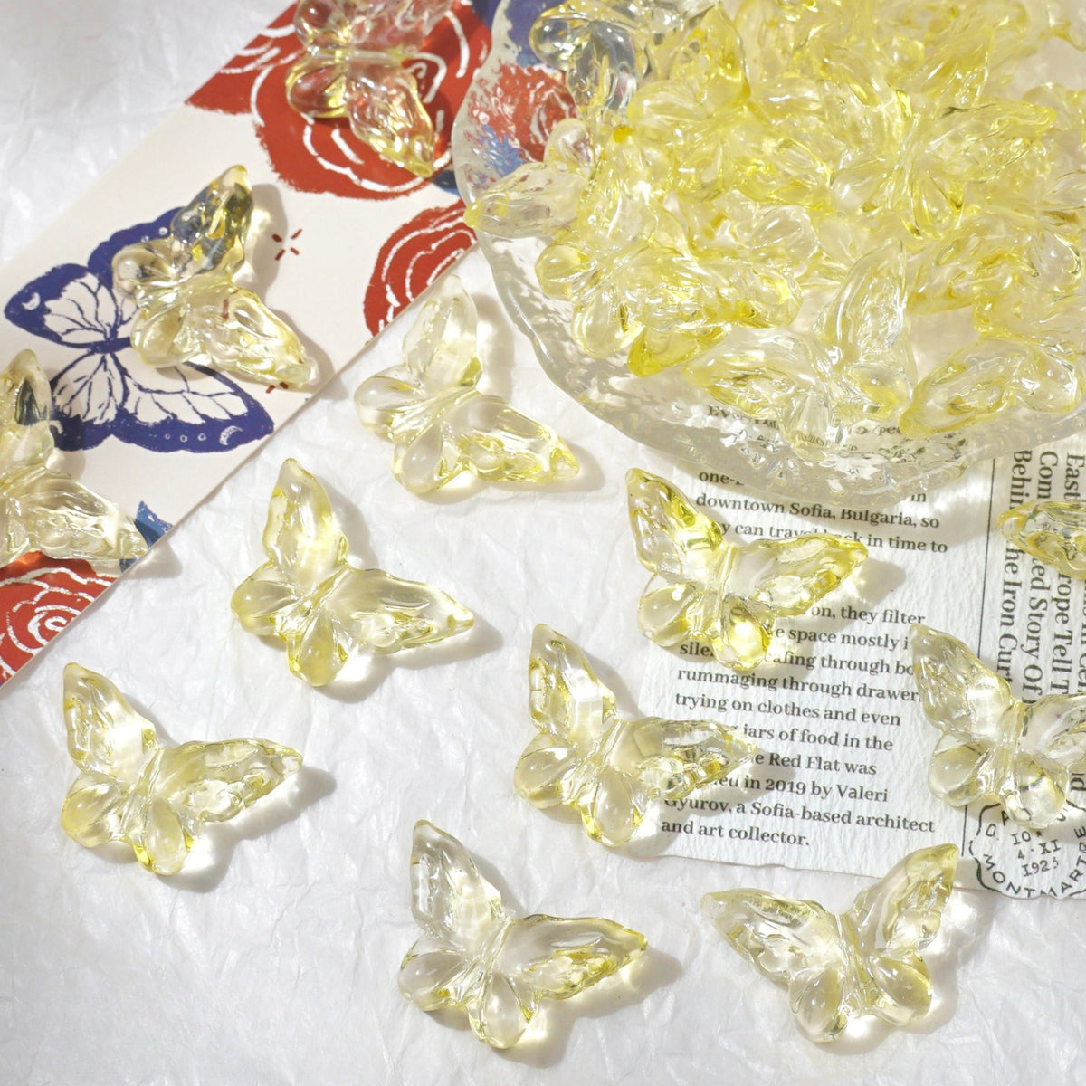 Clear yellow translucent butterfly beads scattered on a white textured surface