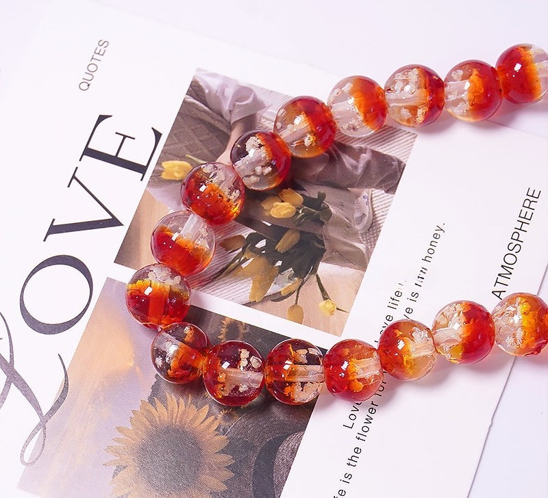 Red two-tone glow-in-the-dark glass beads arranged on a printed LOVE magazine-style card
