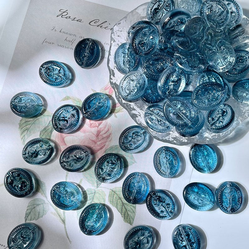 Blue engraved glass beads with embossed medallion designs on white