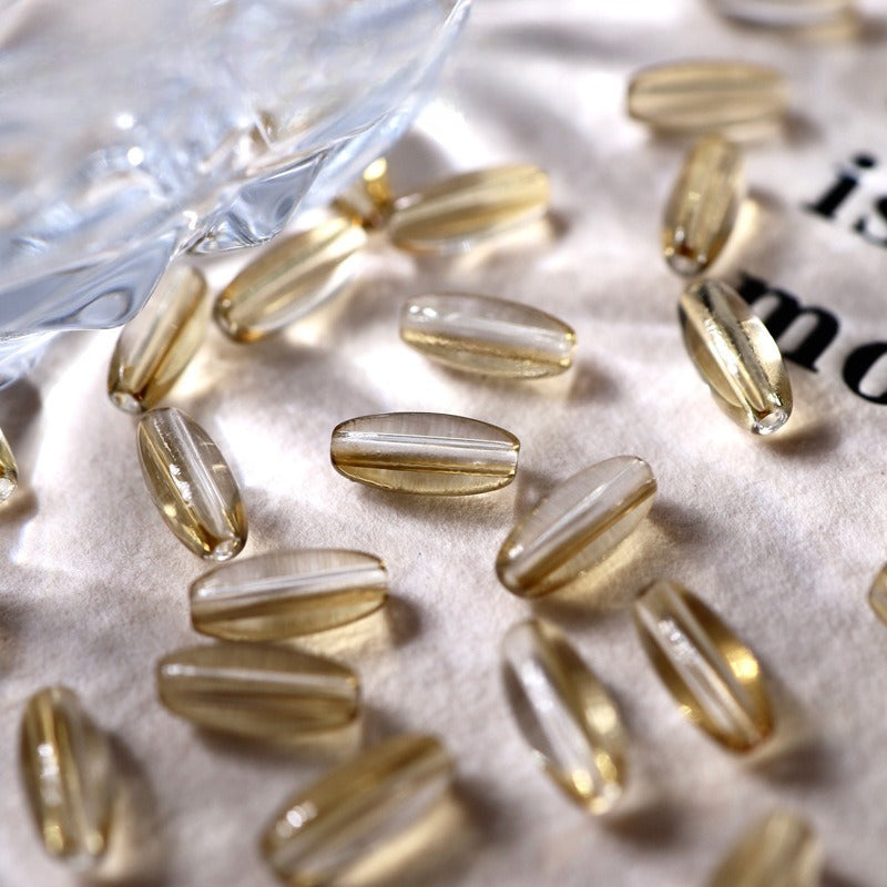 Golden-yellow translucent 4x9mm glazed glass long rice beads scattered
