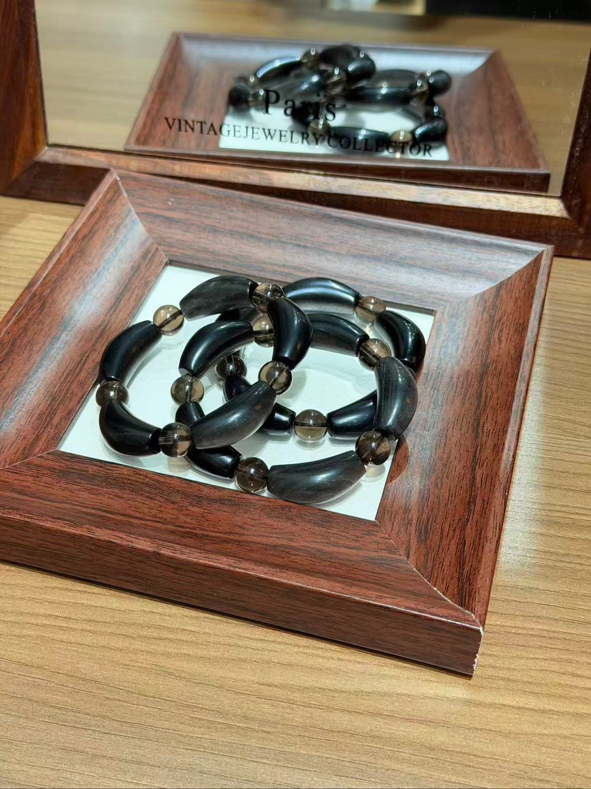 Silver obsidian petal-tube bracelet strands coiled on a tray