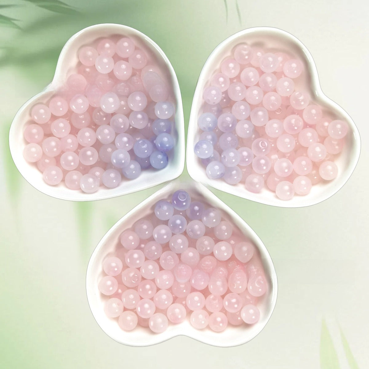 Three heart-shaped bowls of translucent pink and lavender beads