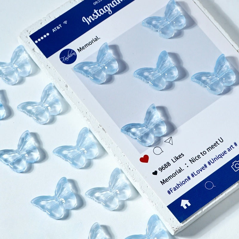 Clear butterfly-shaped glass beads scattered on a white surface next to a printed card