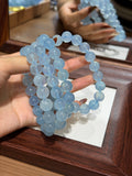 Hand holding premium aquamarine bracelet over tray