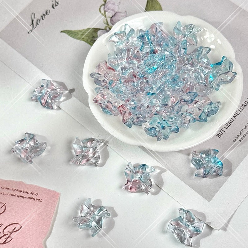 Clear 20mm carved glass windmill beads with light blue and pink iridescent reflections in a white dish on white
