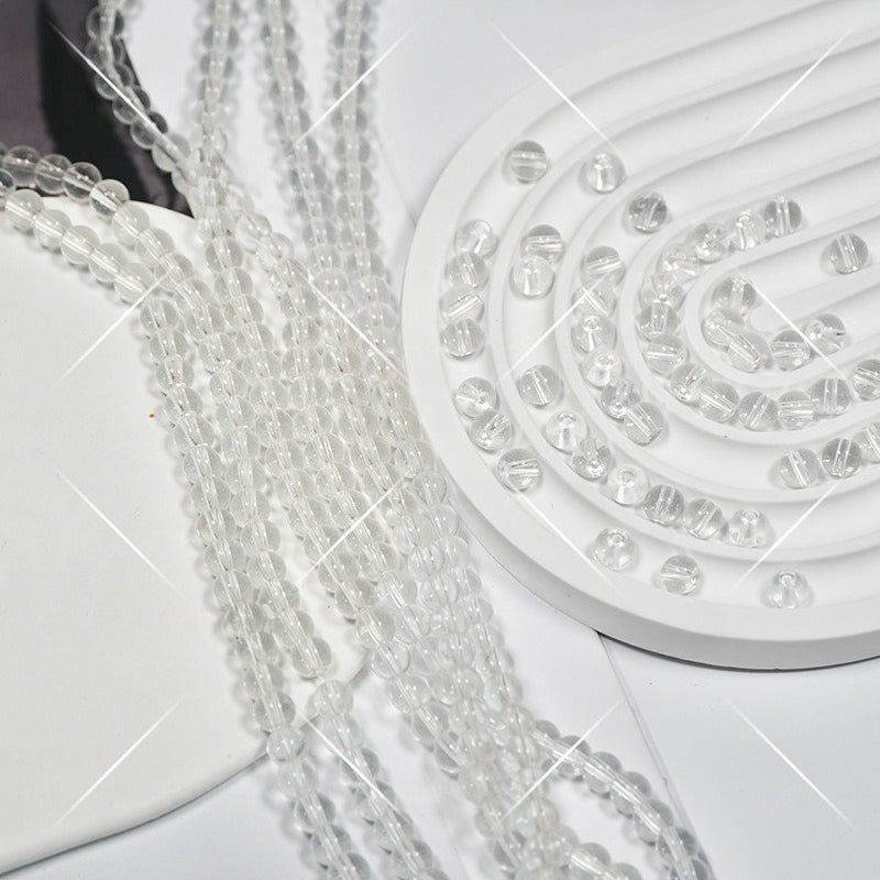Clear faceted glass beads on white spiral display, strands draped over