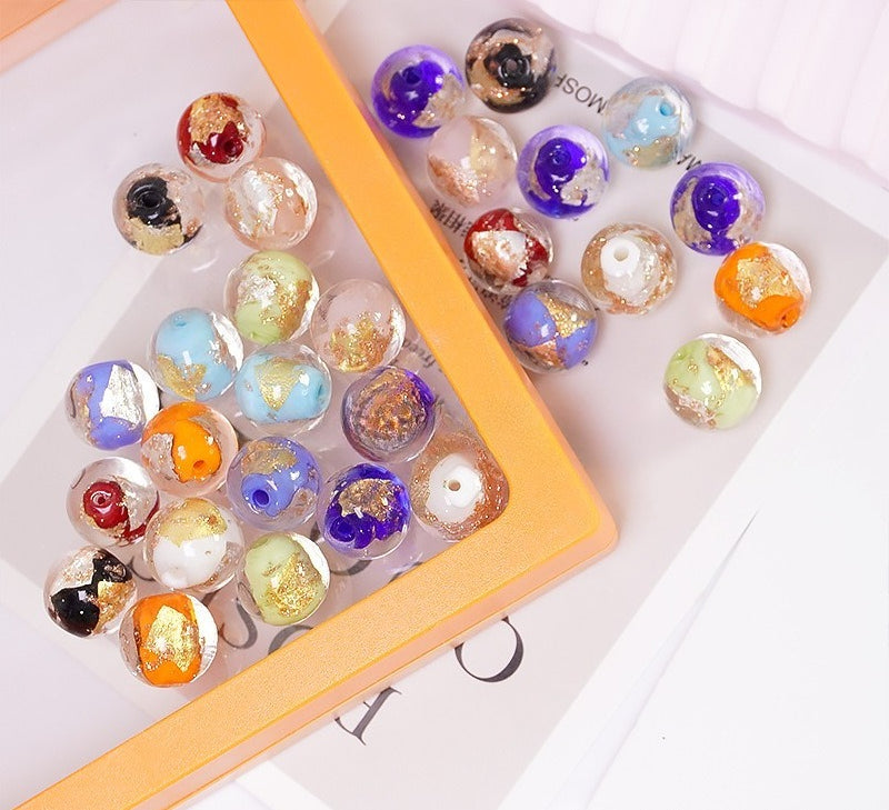 Multicolor gold-leaf glass round beads in an orange-bordered tray on white