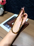 Hand holding a yellow tiger's eye plain strand bracelet, showing golden-brown beads