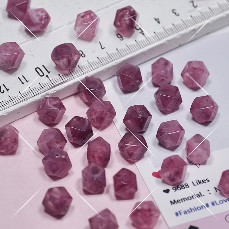 Faceted pink beads scattered on a white and pink surface with a ruler for scale