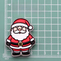 Cartoon Santa Claus acrylic charm with red hat and white beard on green cutting mat