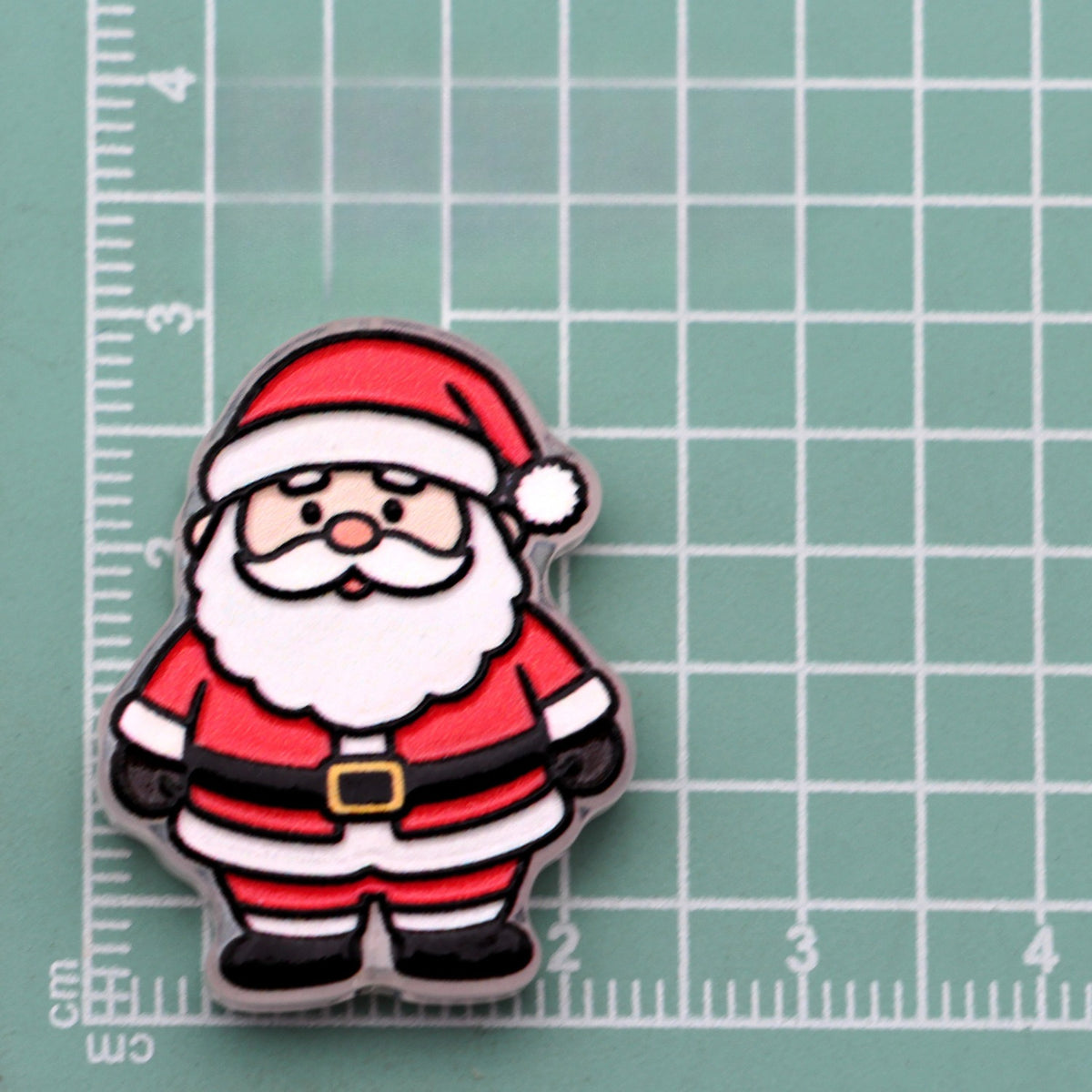 Cartoon Santa Claus acrylic charm with red hat and white beard on green cutting mat