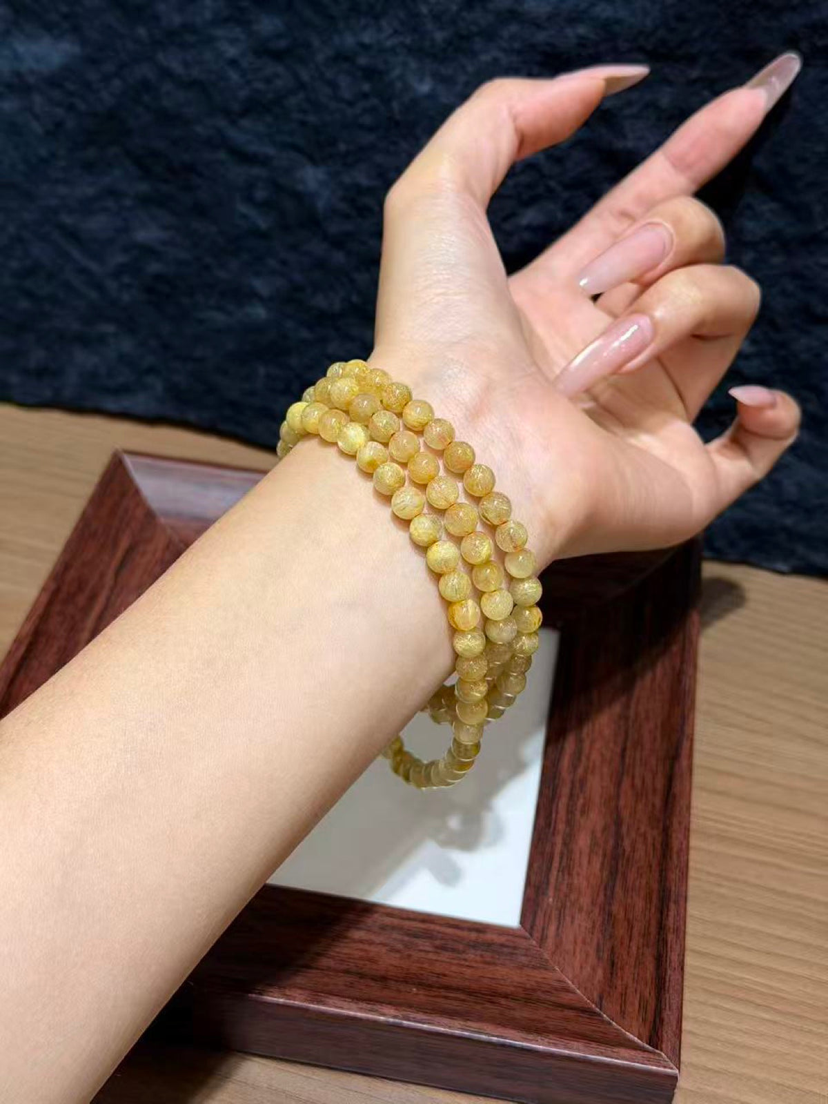 Golden rutilated quartz triple-wrap bracelet worn on a wrist