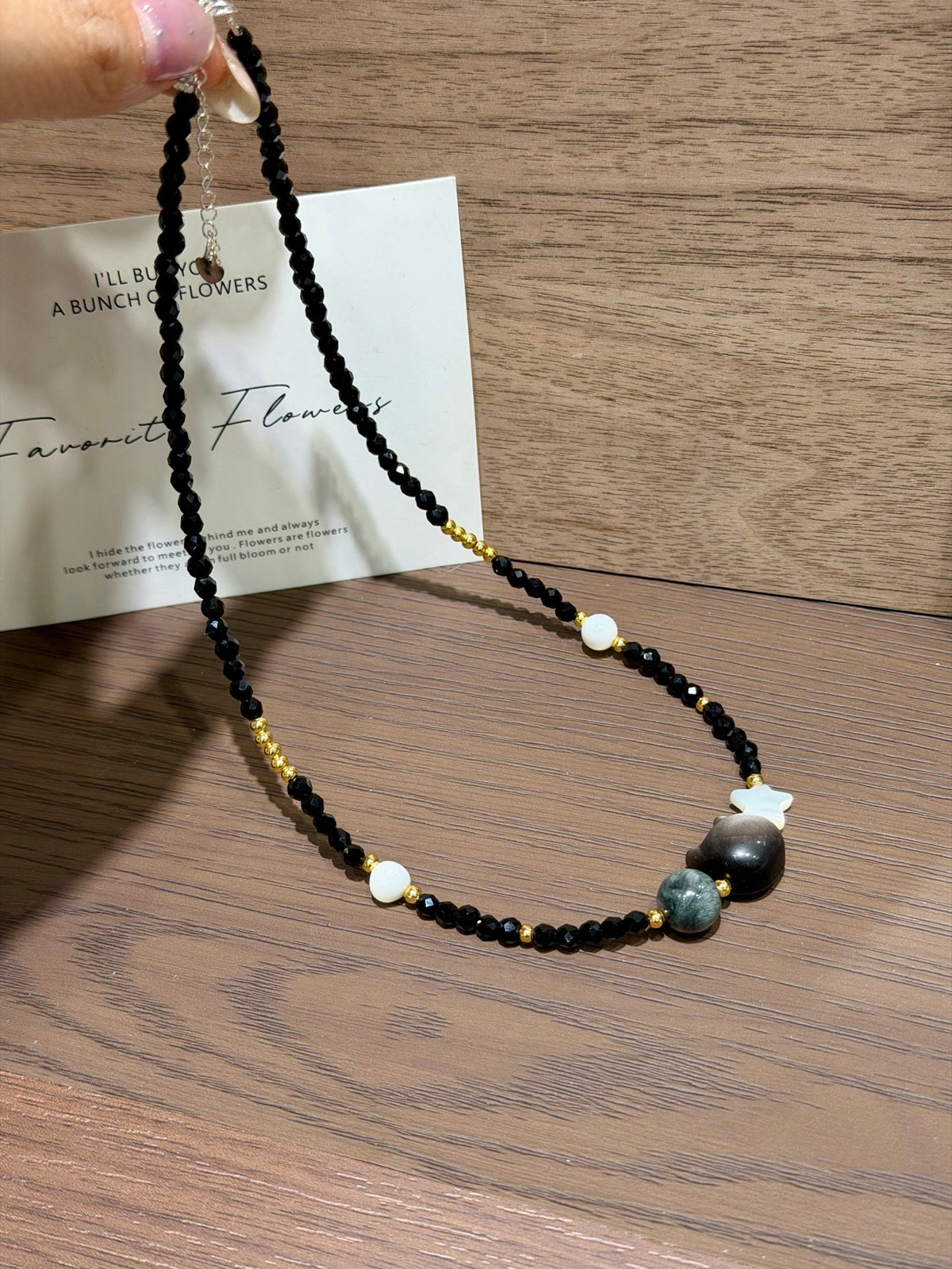Hand holding midnight cat hawk's eye strand necklace
