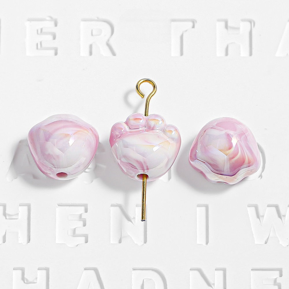 Three pink and white marbled glass beads with gold metal hooks on a white background.