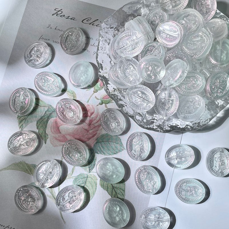 Clear engraved glass beads with embossed designs on white floral paper