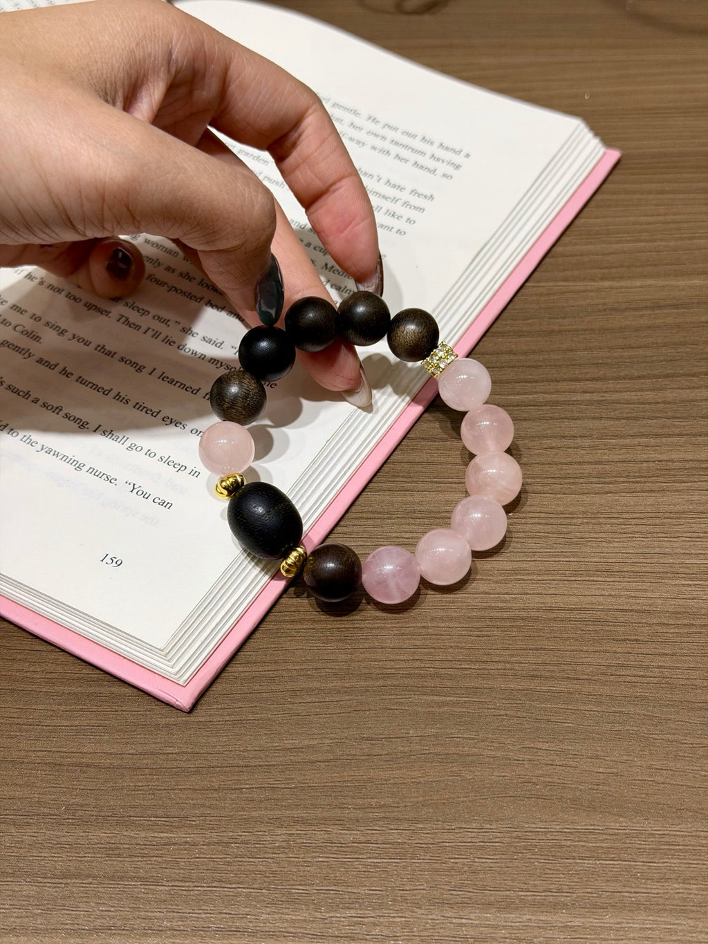 Pink Quartz & Agarwood Bracelet held over open book