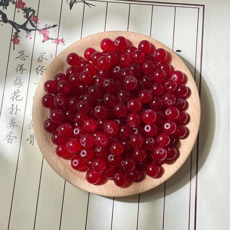 Translucent red round beads on a wooden plate with calligraphy background