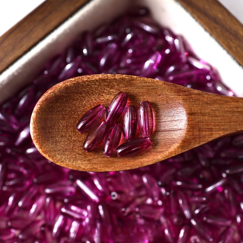 Deep purple translucent 4x9mm glazed glass long rice beads in a wooden spoon