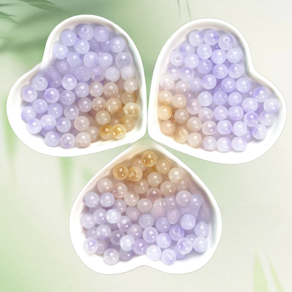 Three heart-shaped bowls of translucent pastel beads on pale green