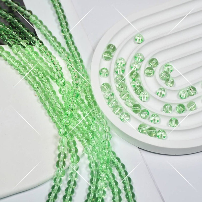 Green faceted round glass beads in strands on white spiral display tray