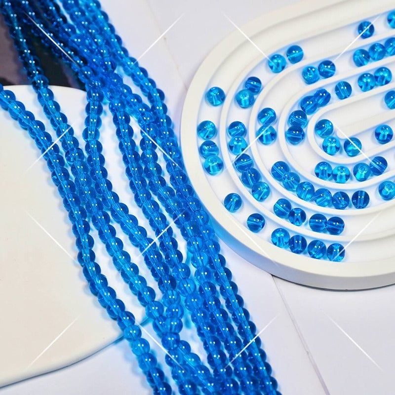 Blue translucent round glass beads in strands on white spiral display tray